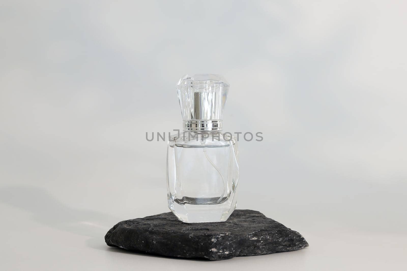 Unbranded perfume bottle standing on stone podium. Perfume presentation on the white background. Mockup. Trending concept in natural materials. Women's and men's essence. Natural cosmetic. by creativebird