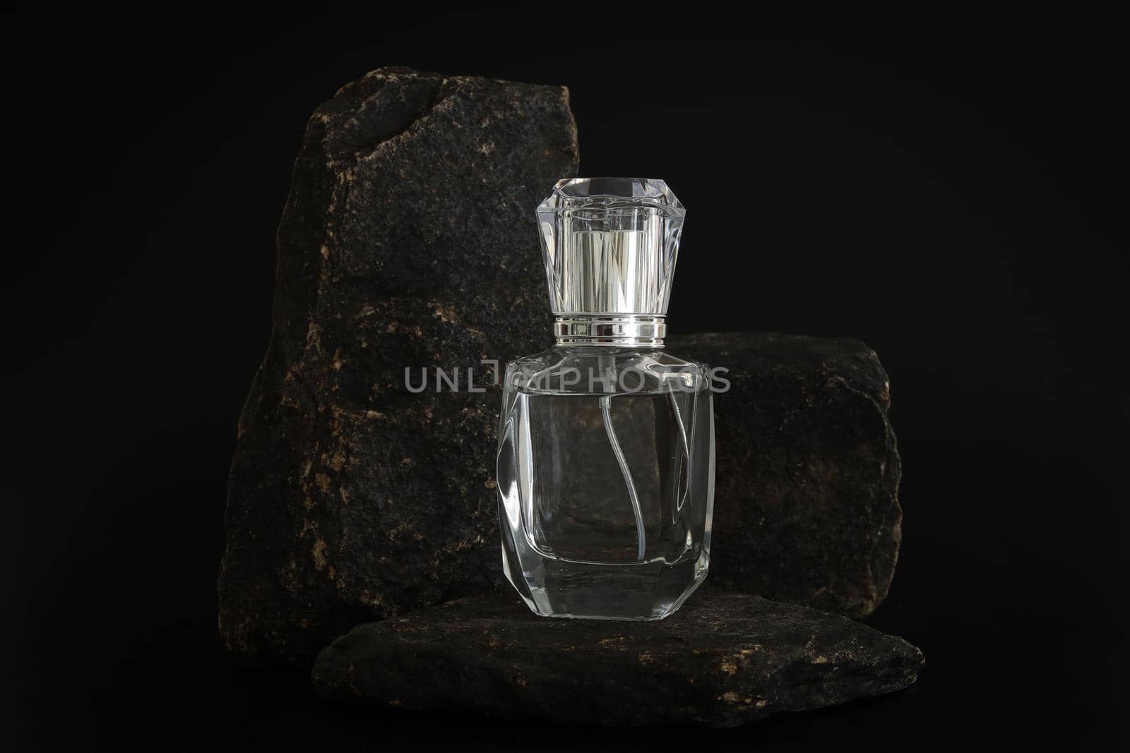 Unbranded perfume bottle standing on stone podium. Perfume presentation on the black background. Mockup. Trending concept in natural materials. Women's and men's essence. Natural cosmetic. by creativebird