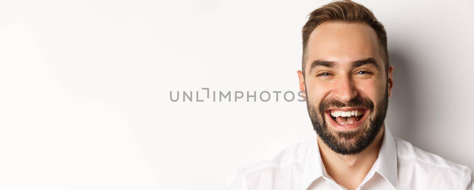 Emotions and people concept. Headshot of happy attractive man laughing and smiling, express rejoice, white background.