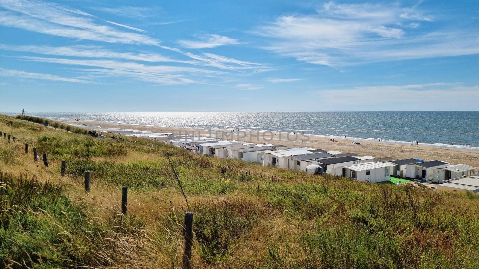 View from dunes on North Sea city beach on a sunny summer weekend. Typical pavilions. Zandvoort, Netherlands.
