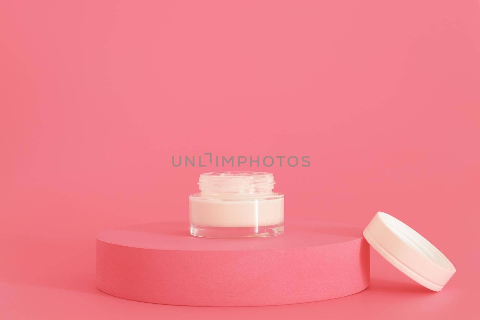 Cosmetic cream packaging standing on pink podium. Cream presentation on the pink background. Mockup