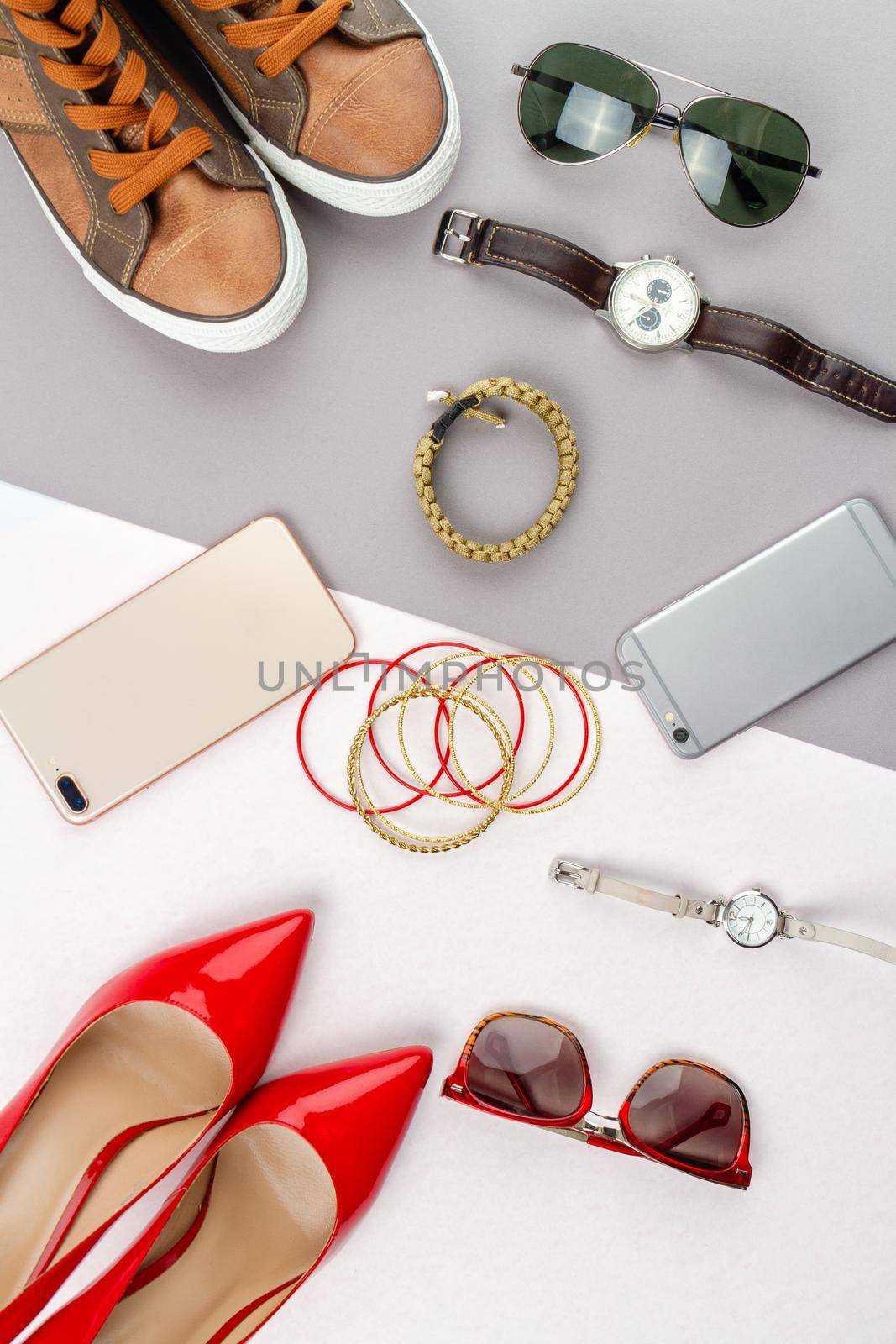 Flat lay composition of womens and mens accessories. Vertical shot top view contrast of male and female belongings.