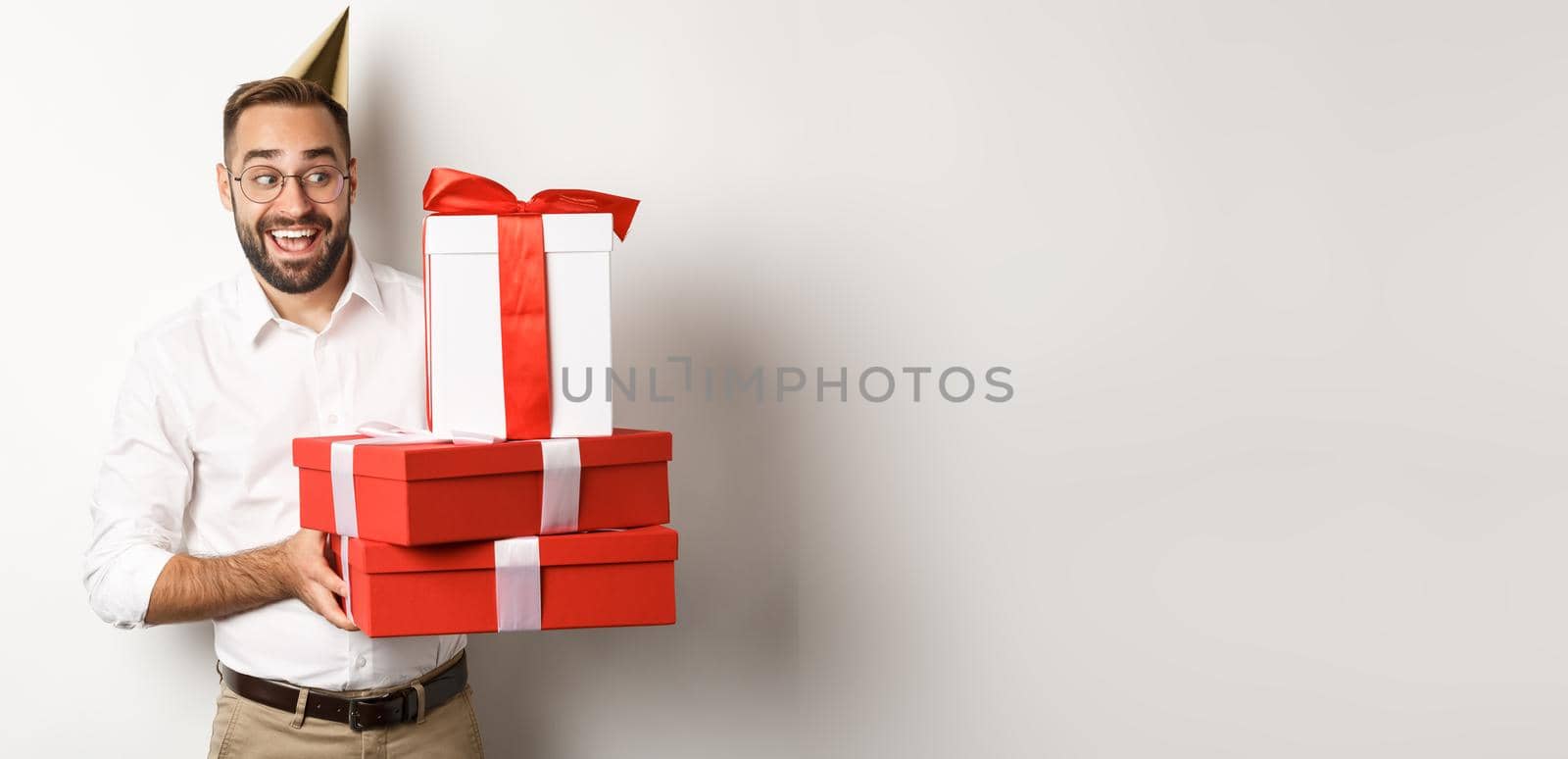 Holidays and celebration. Excited man having birthday party and receiving gifts, looking happy, standing over white background by Benzoix
