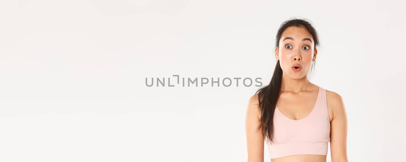 Sport, wellbeing and active lifestyle concept. Close-up of excited and amazed asian fitness girl, cute brunette in sportsbra say wow, gasping and looking left at your logo or promo banner.