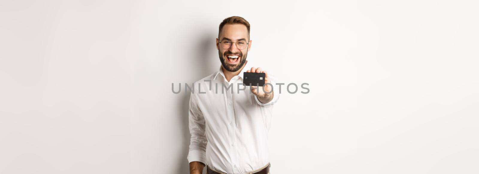 Excited caucasian man in glasses showing credit card, concept of shopping.