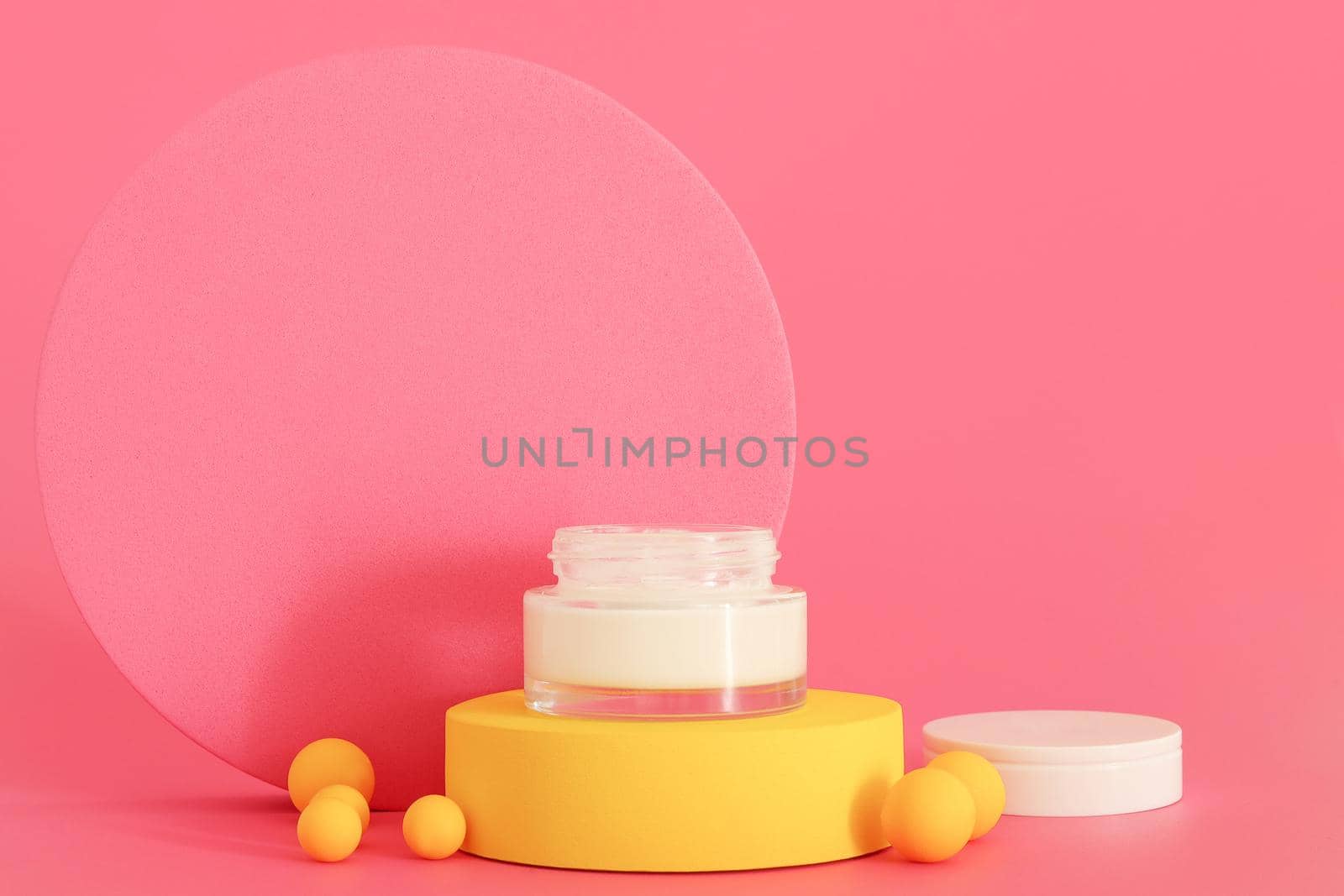 Cosmetic cream packaging standing on yellow podium. Free space for text or logo, copy space. Cream presentation on the pink background. Mockup