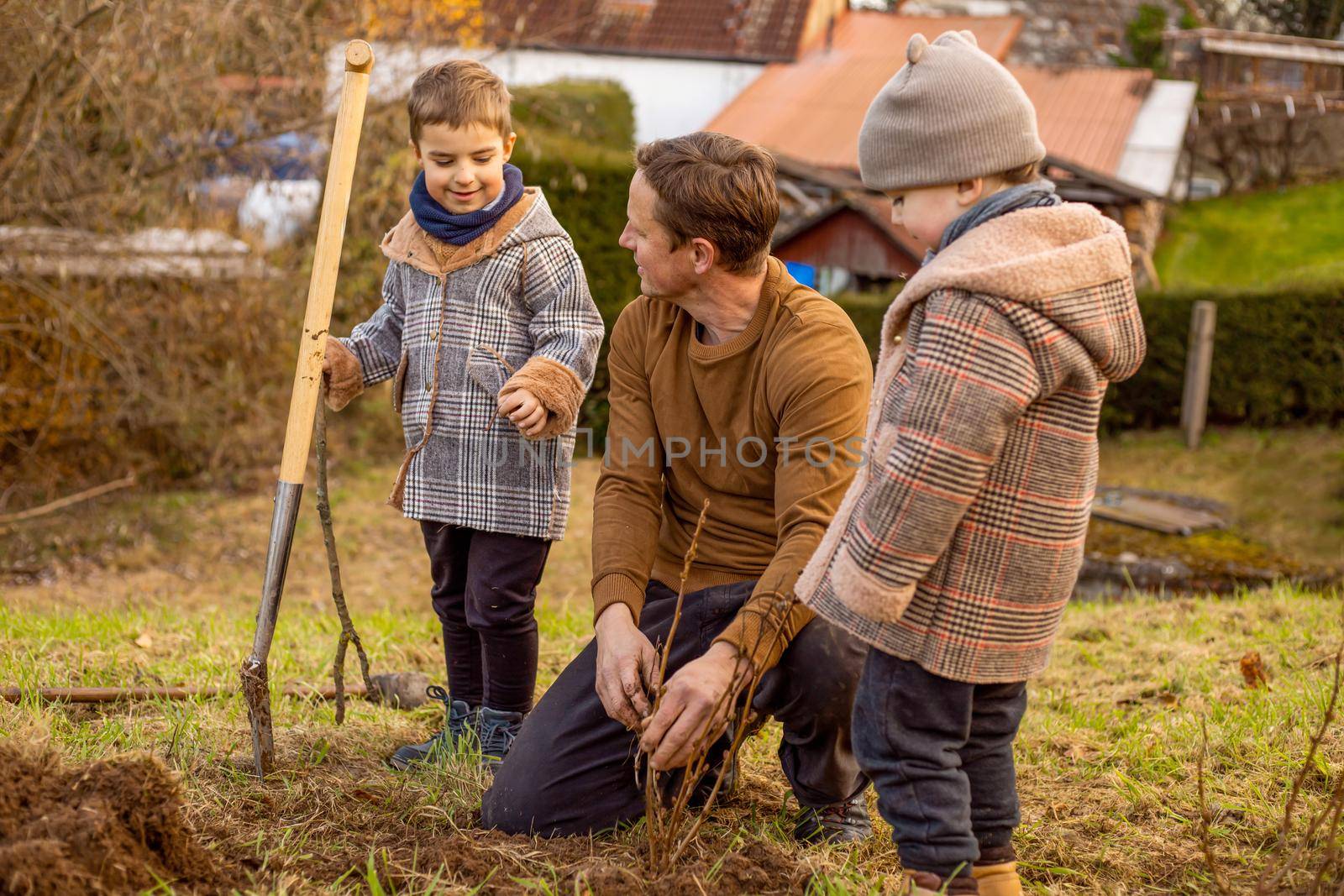 Man with kids plants tree in the garden. Nature, environment and ecology concept. Father with his children outdoor, family time. by creativebird