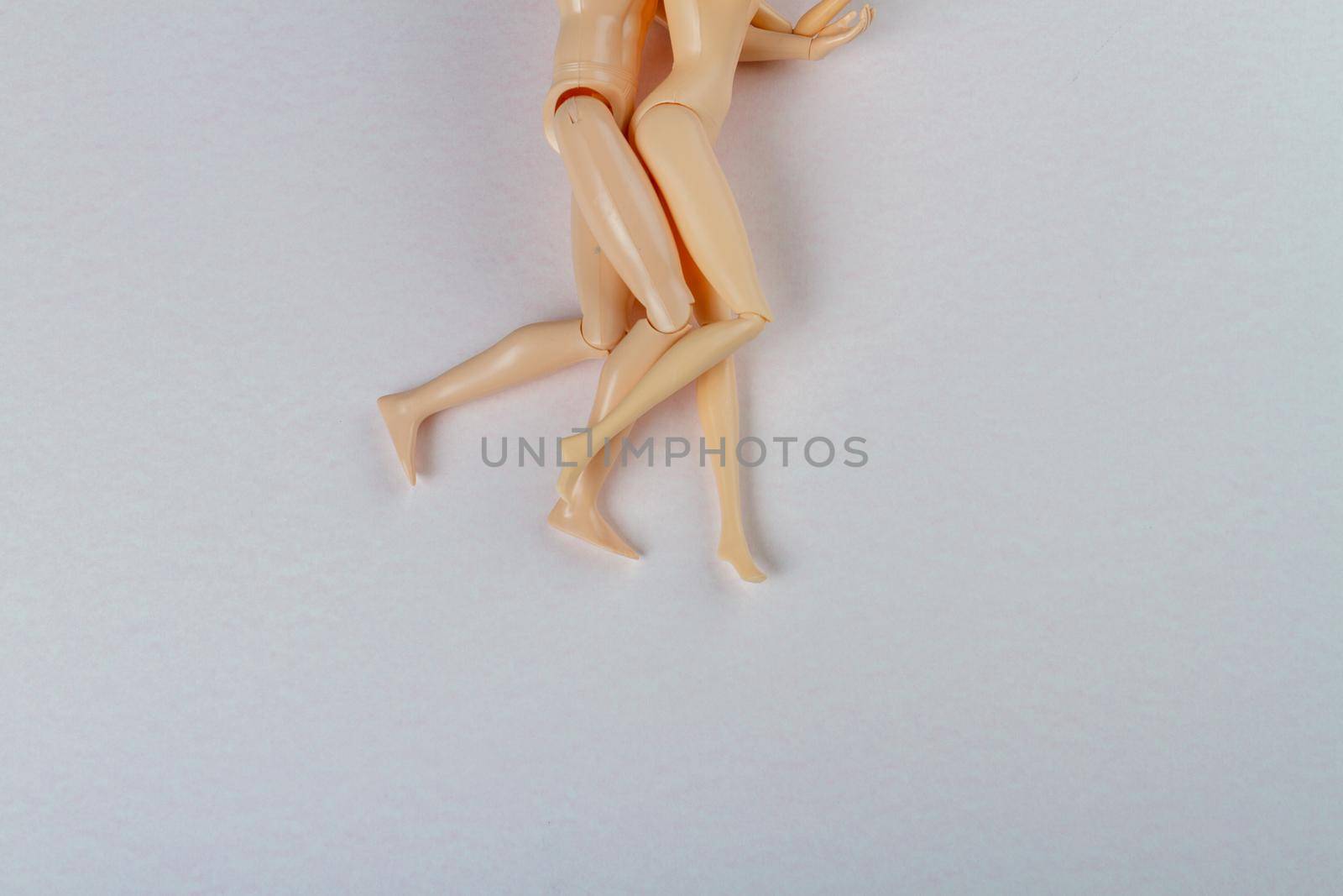 Top view naked doll couple on white surface. Toy hugging lovers.