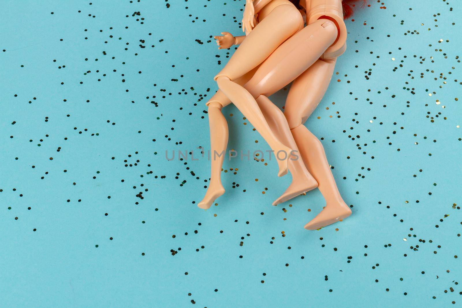 Naked male and female dolls on blue surface with sequins. by super_picture