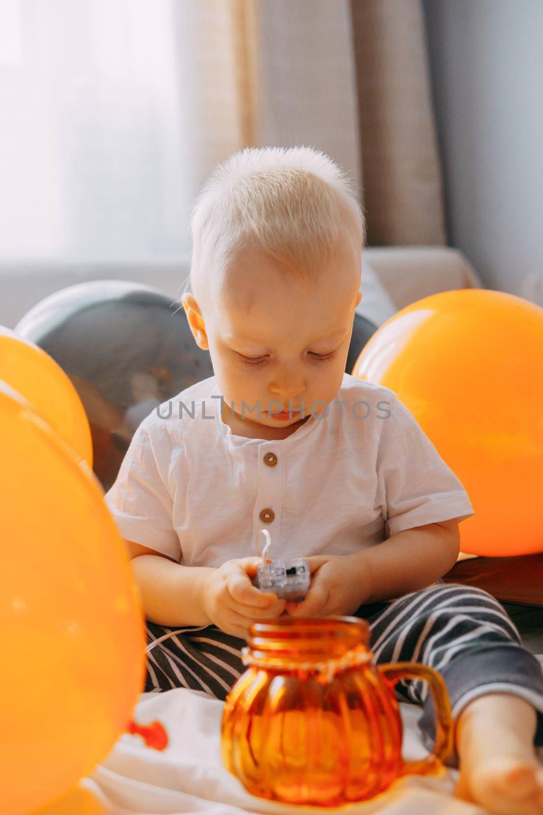 Children's Halloween - a boy in a carnival costume with orange and black balloons at home. Ready to celebrate Halloween by Annu1tochka