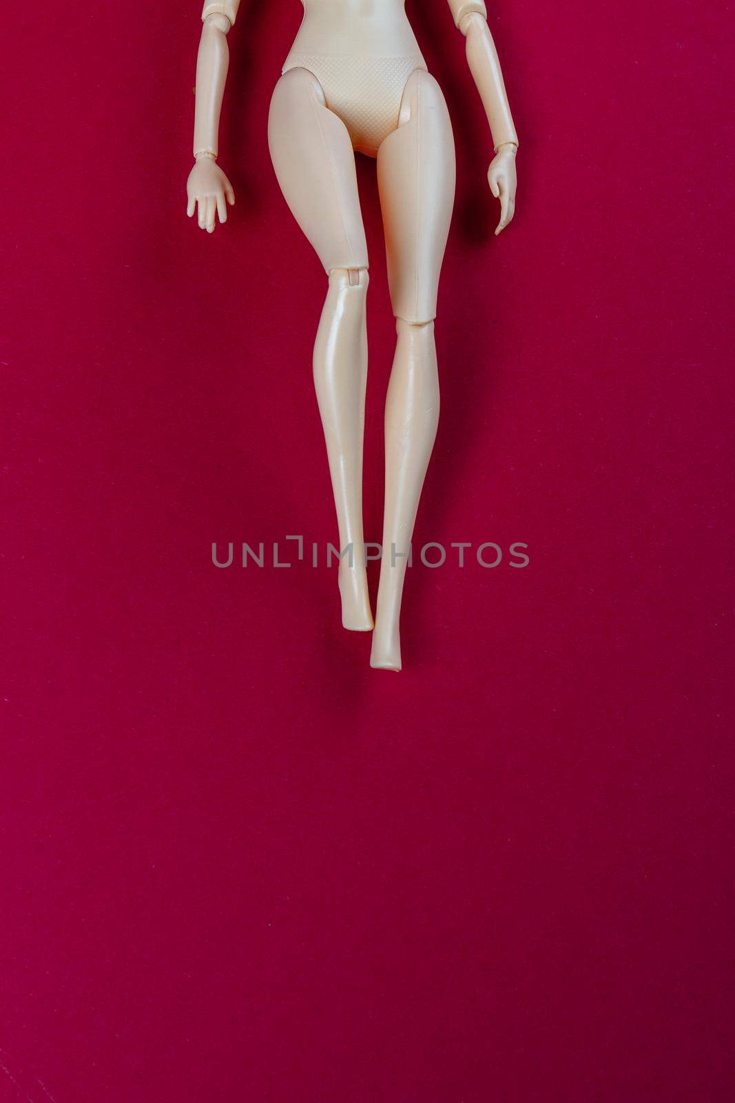 Naked female mannequin doll on red surface. Sexy slim body and copy space.