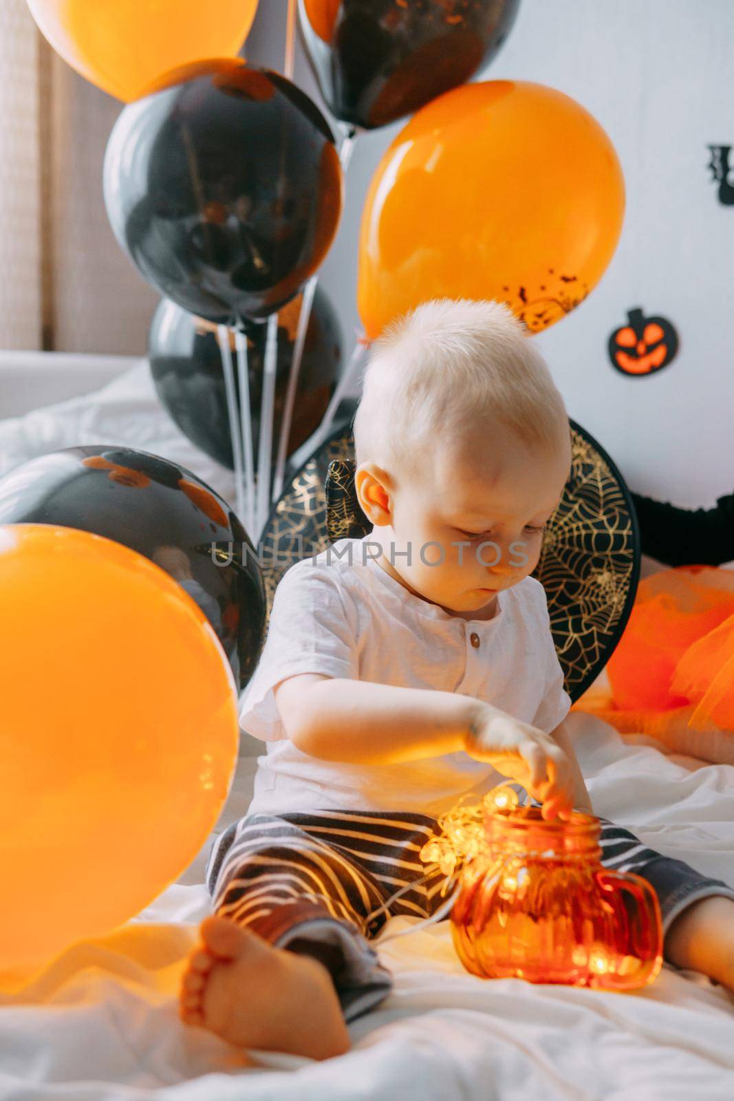 Children's Halloween - a boy in a carnival costume with orange and black balloons at home. Ready to celebrate Halloween