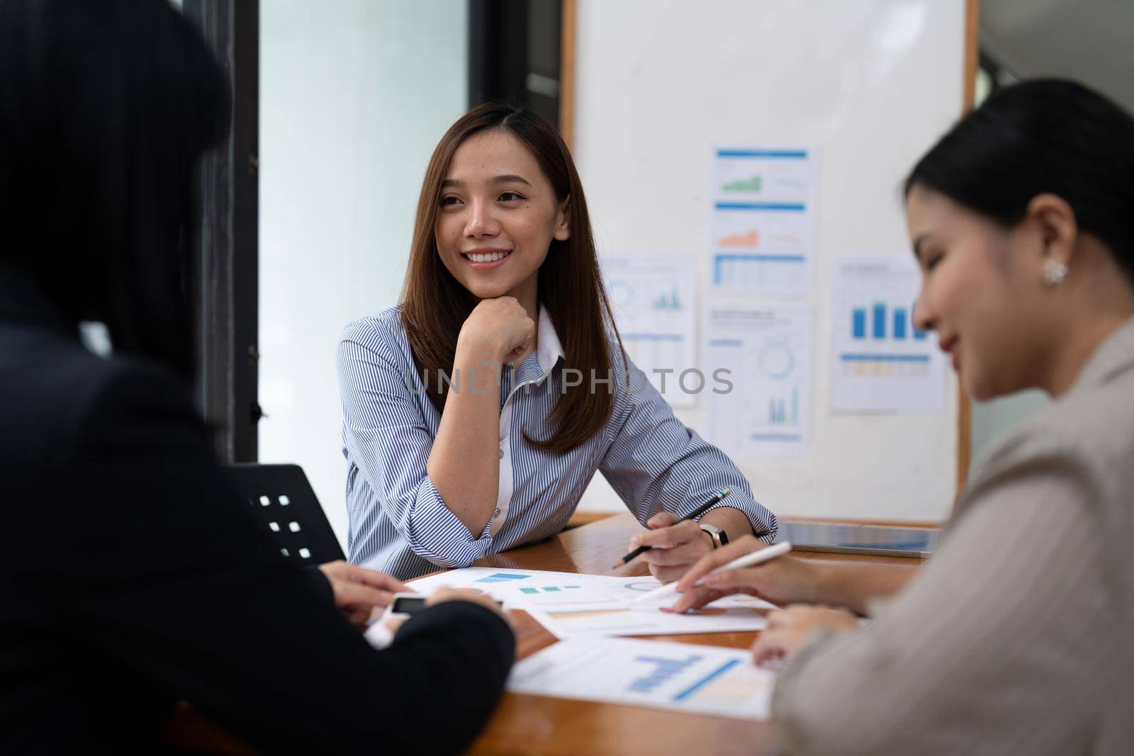 A young asian woman is having a business meeting with her team colleagues in a conference room