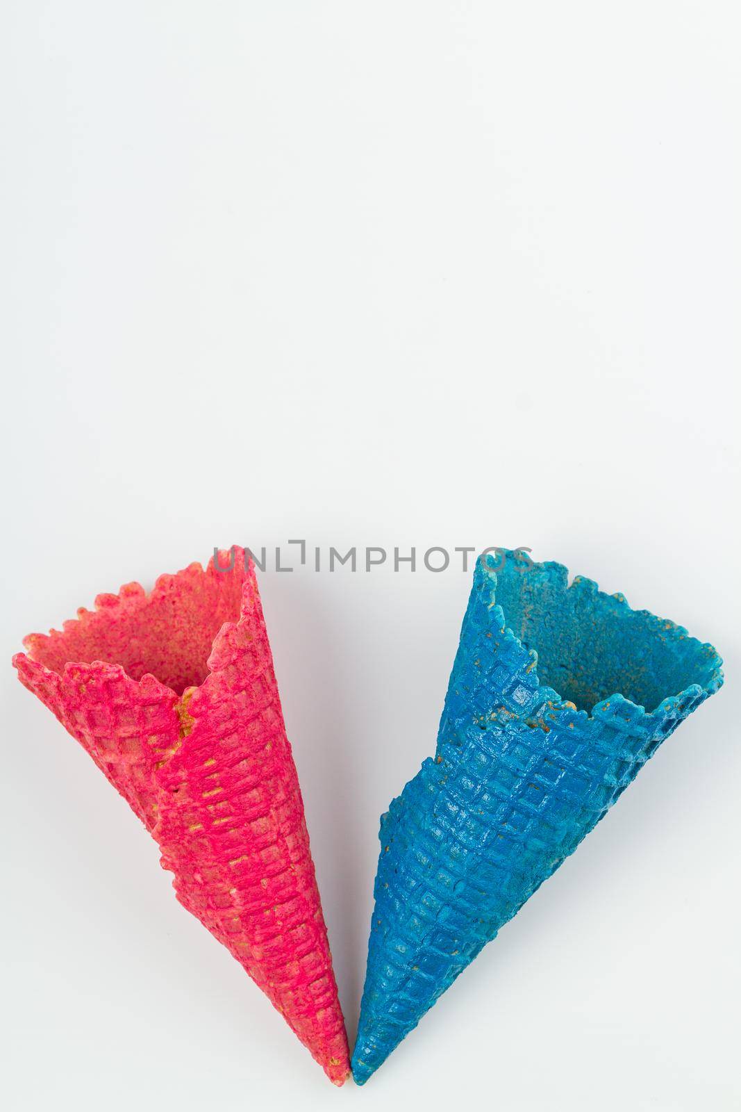 Pink and blue ice cream waffle cones on white background. Concept of difference between men and women.
