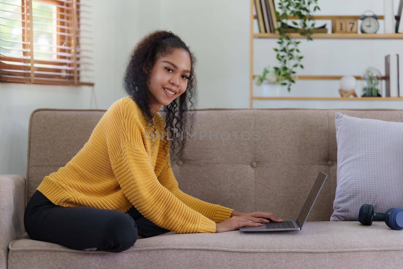 Attractive smiling young woman using laptop on sofa at home. lifestyle concept by itchaznong