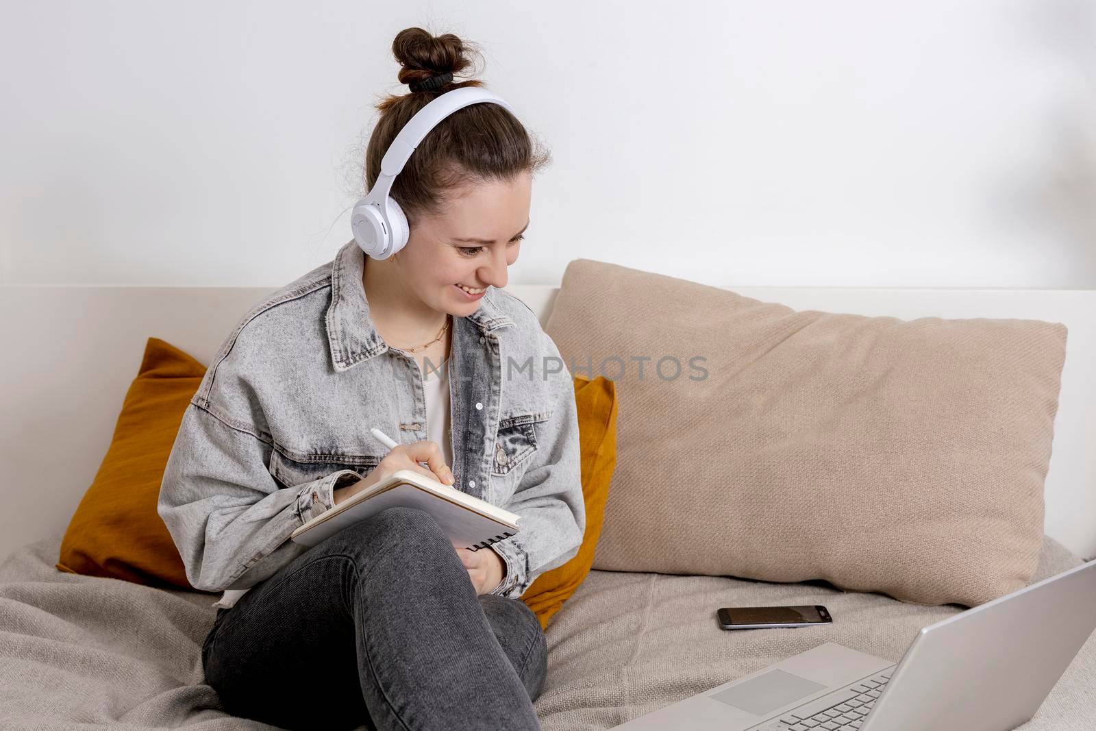 Young beautiful woman with casual clothes sitting on the bed at home with laptop computer and studying. Girl using e-learning platform to make a video call with her teacher. Distance education. by creativebird