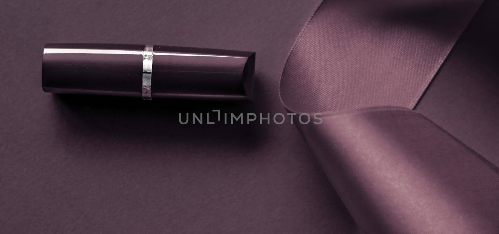 Cosmetic branding, glamour lip gloss and shopping sale concept - Luxury lipstick and silk ribbon on dark purple holiday background, make-up and cosmetics flatlay for beauty brand product design