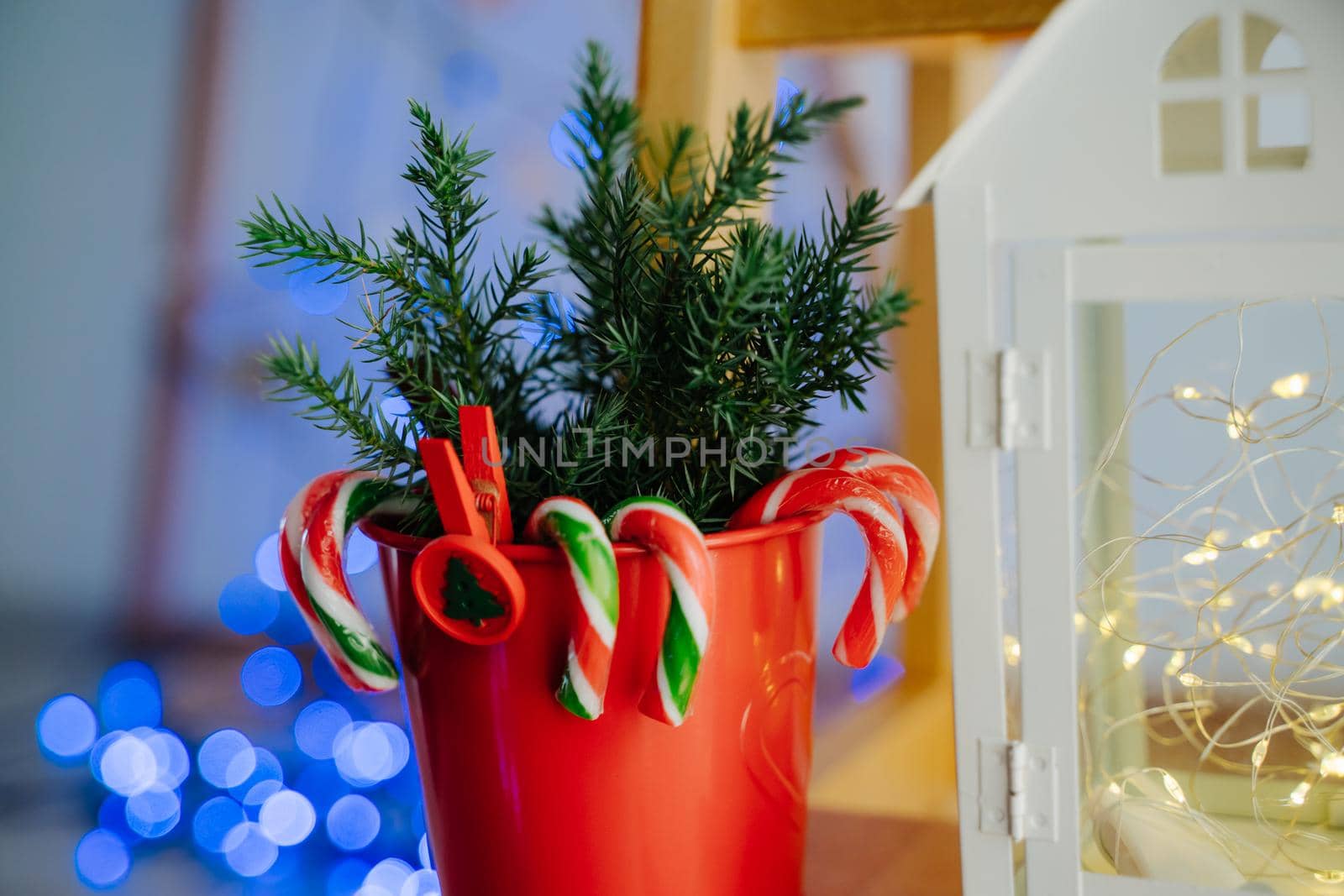 Composition of red pots with coniferous branches and ledins canes and a white house. Christmas decor. by Rodnova