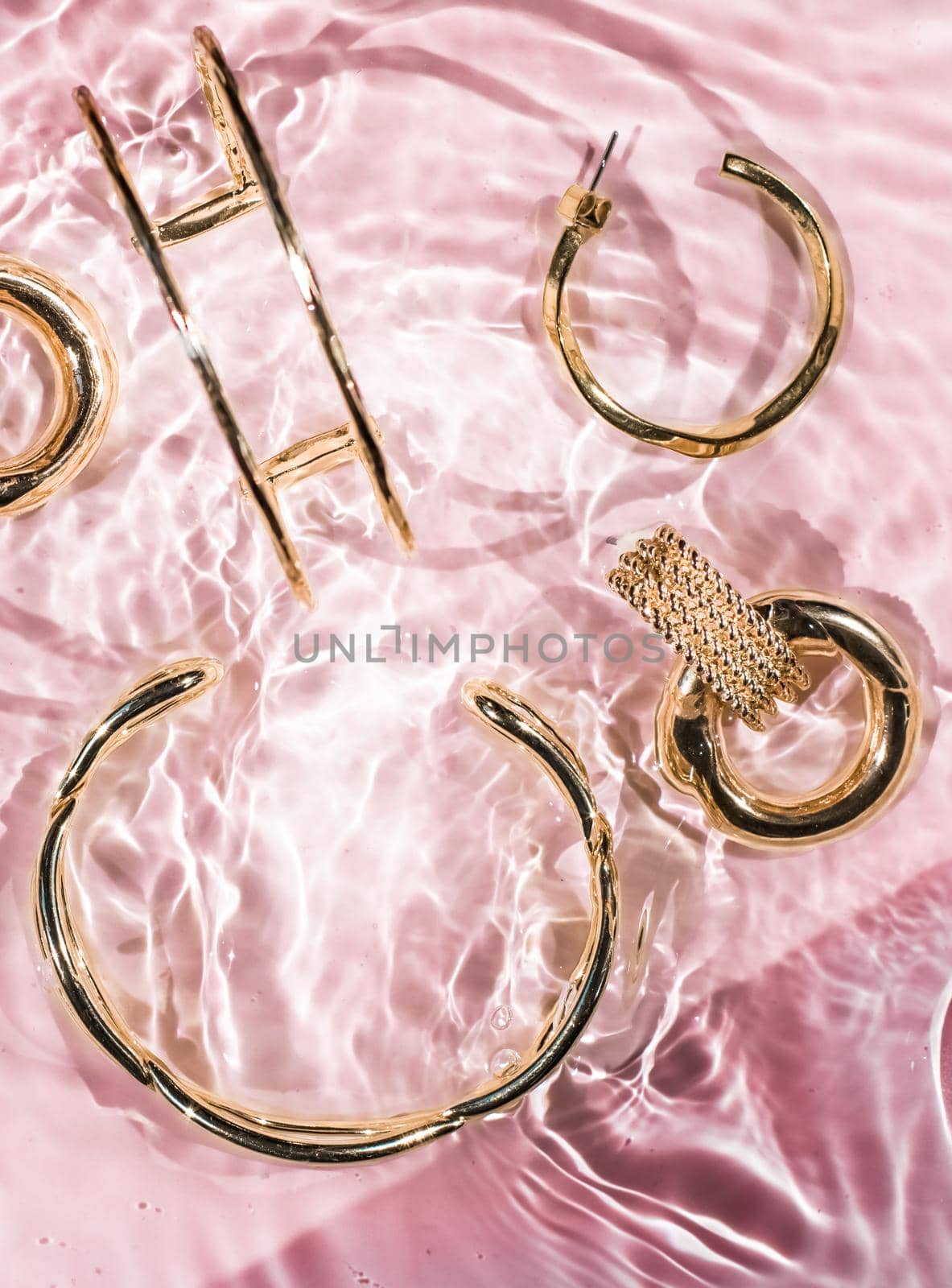 Jewellery branding, fashion gift and luxe shopping concept - Golden bracelets, earrings, rings, jewelery on pink water background, luxury glamour and holiday beauty design for jewelry brand ads