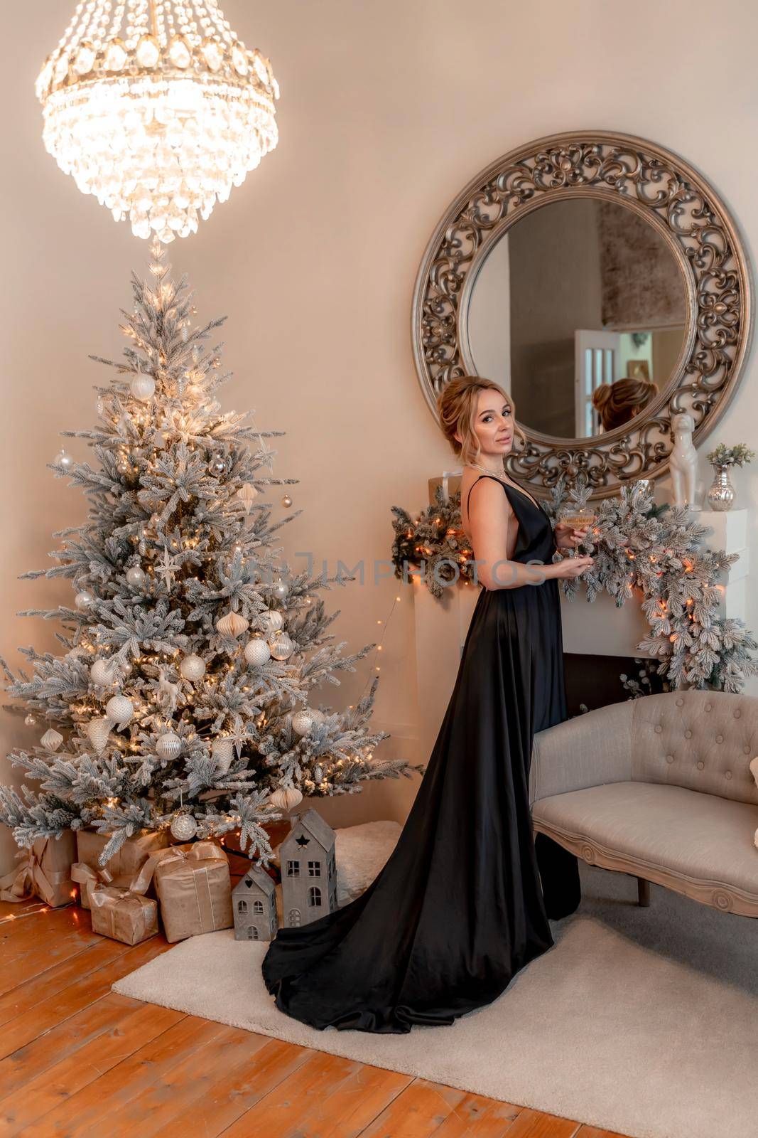 Portrait of a wealthy mature woman with evening make-up and hairstyle posing in a black dress on the background of the Christmas room. Luxurious lifestyle. Christmas holidays concept by Matiunina