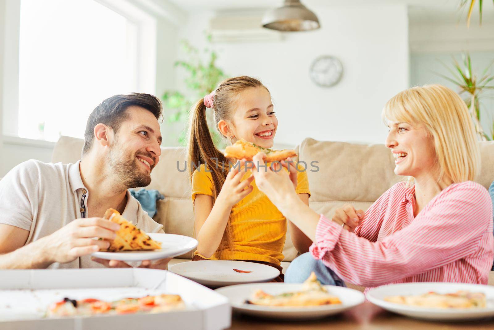 Family having meal, lunch or dinner, eating pizza and having fun at home