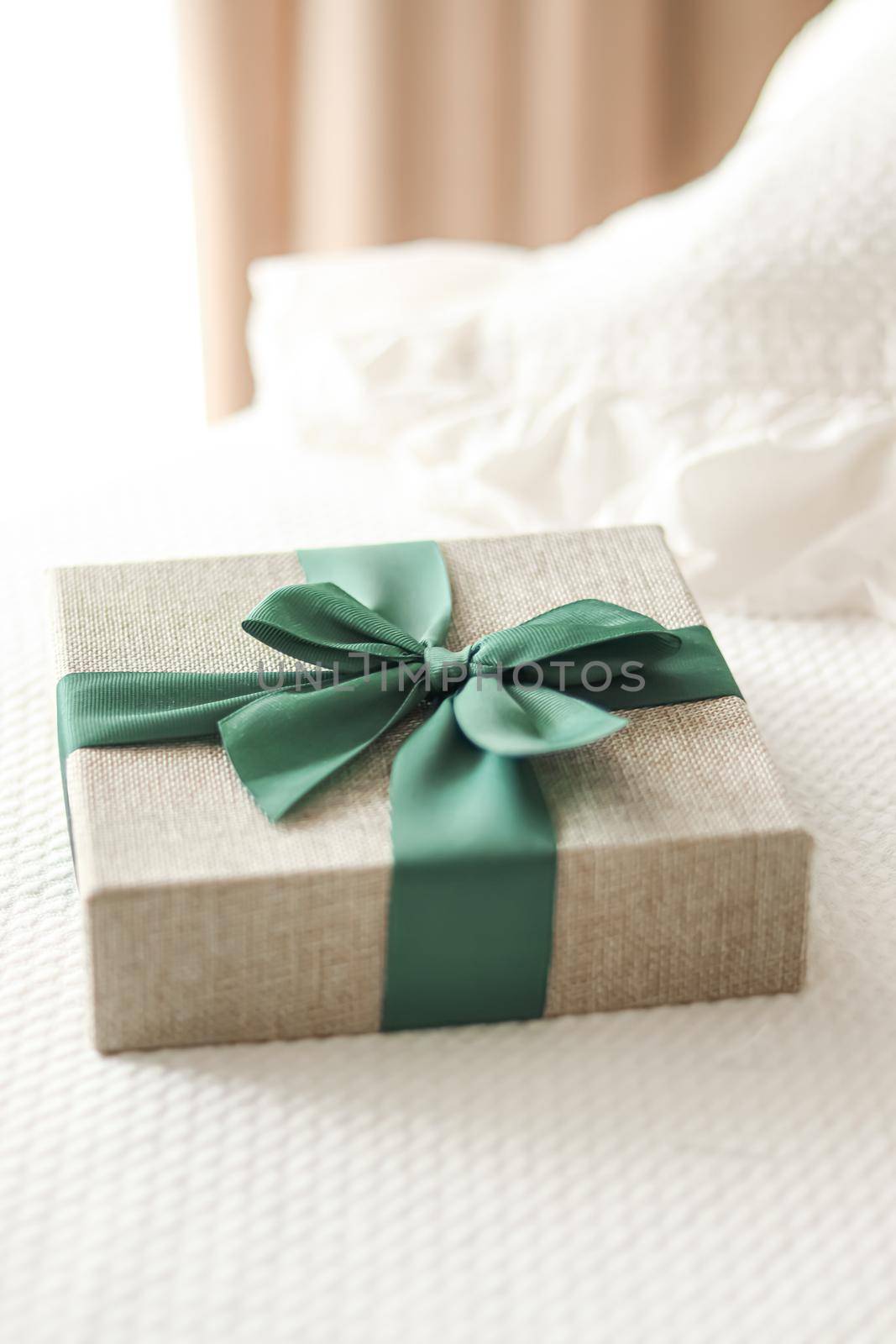 Holiday present and luxury online shopping delivery, wrapped linen gift box with green ribbon on bed in bedroom, chic countryside style, close-up