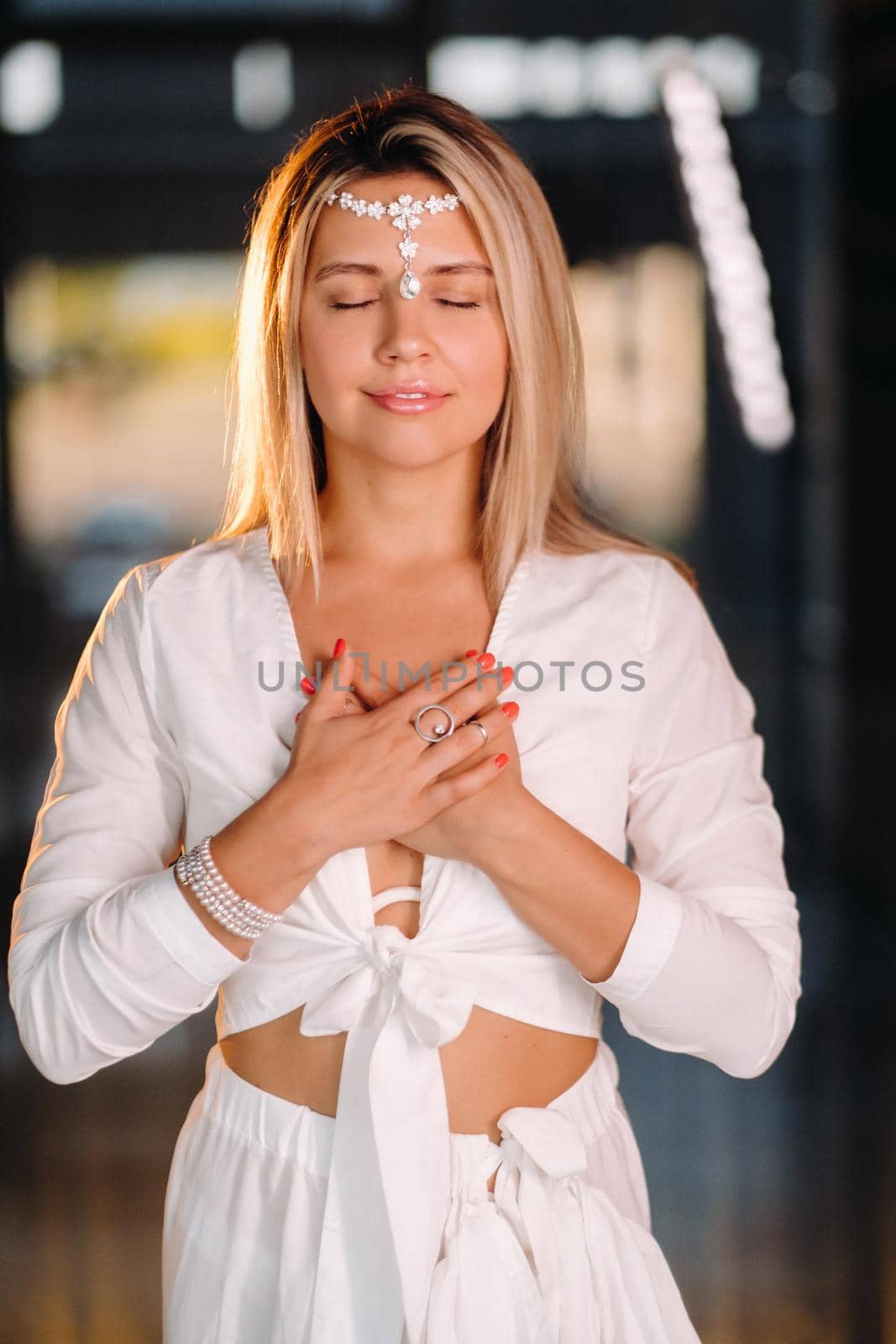 Portrait of a smiling girl in a white dress with her palms clasped in front of her by Lobachad