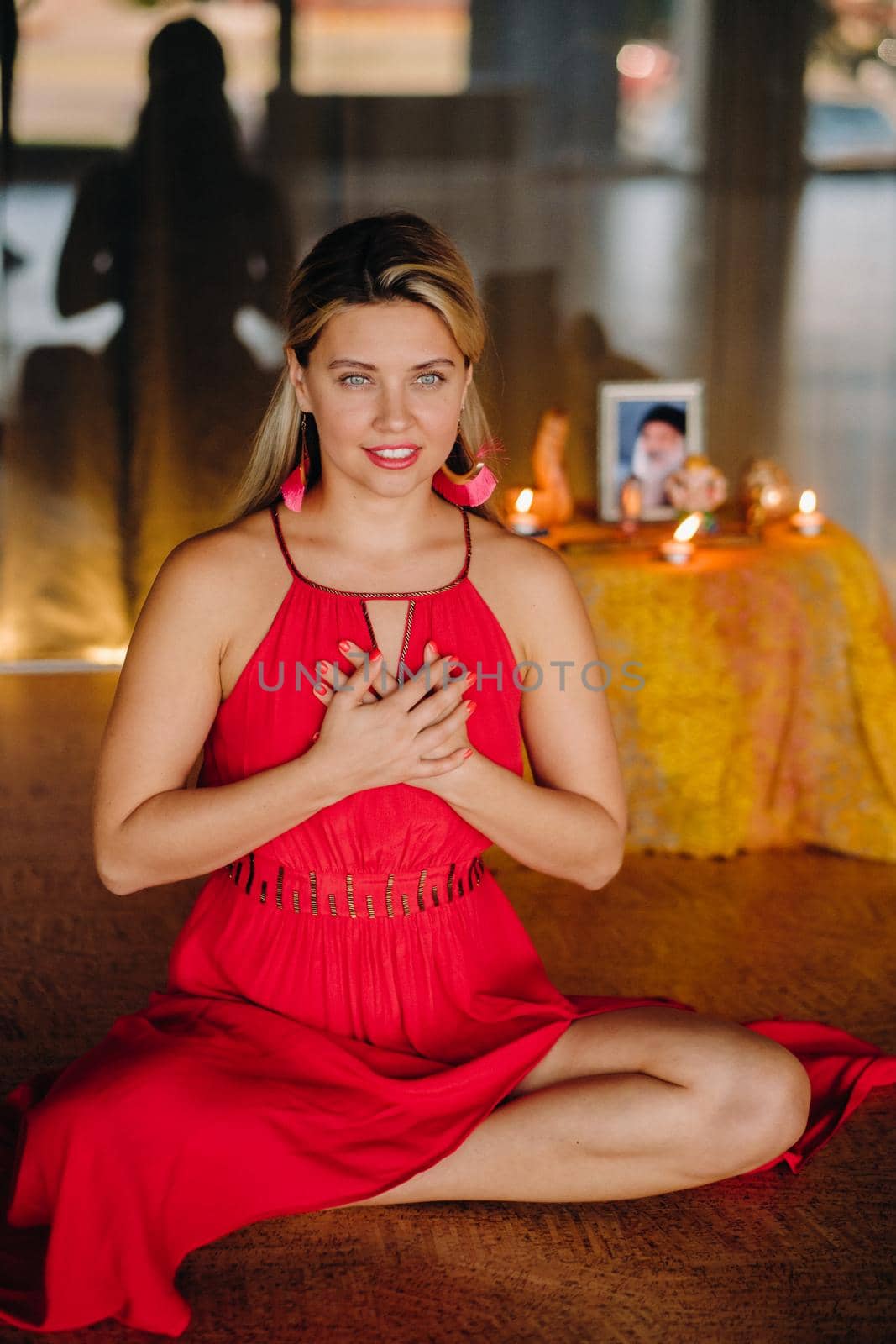 Meditation and concentration. a woman in a red dress sitting on the floor is practicing medicine indoors . Calm and relaxation.