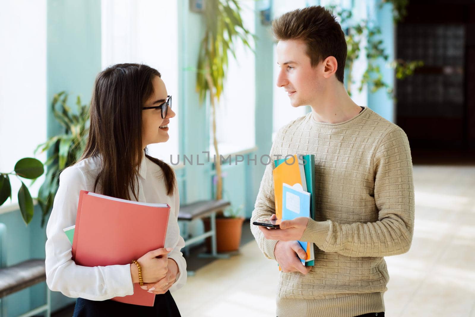 Two students communicate during break holding learning materials afraid to express their feelings to one another