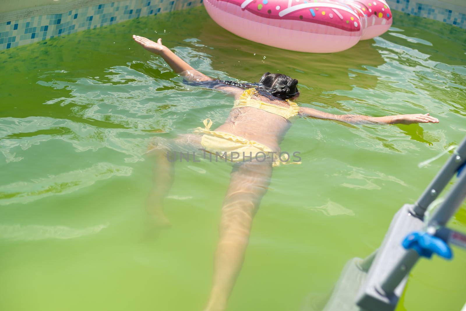 little girl in the green water of very dirty pool.
