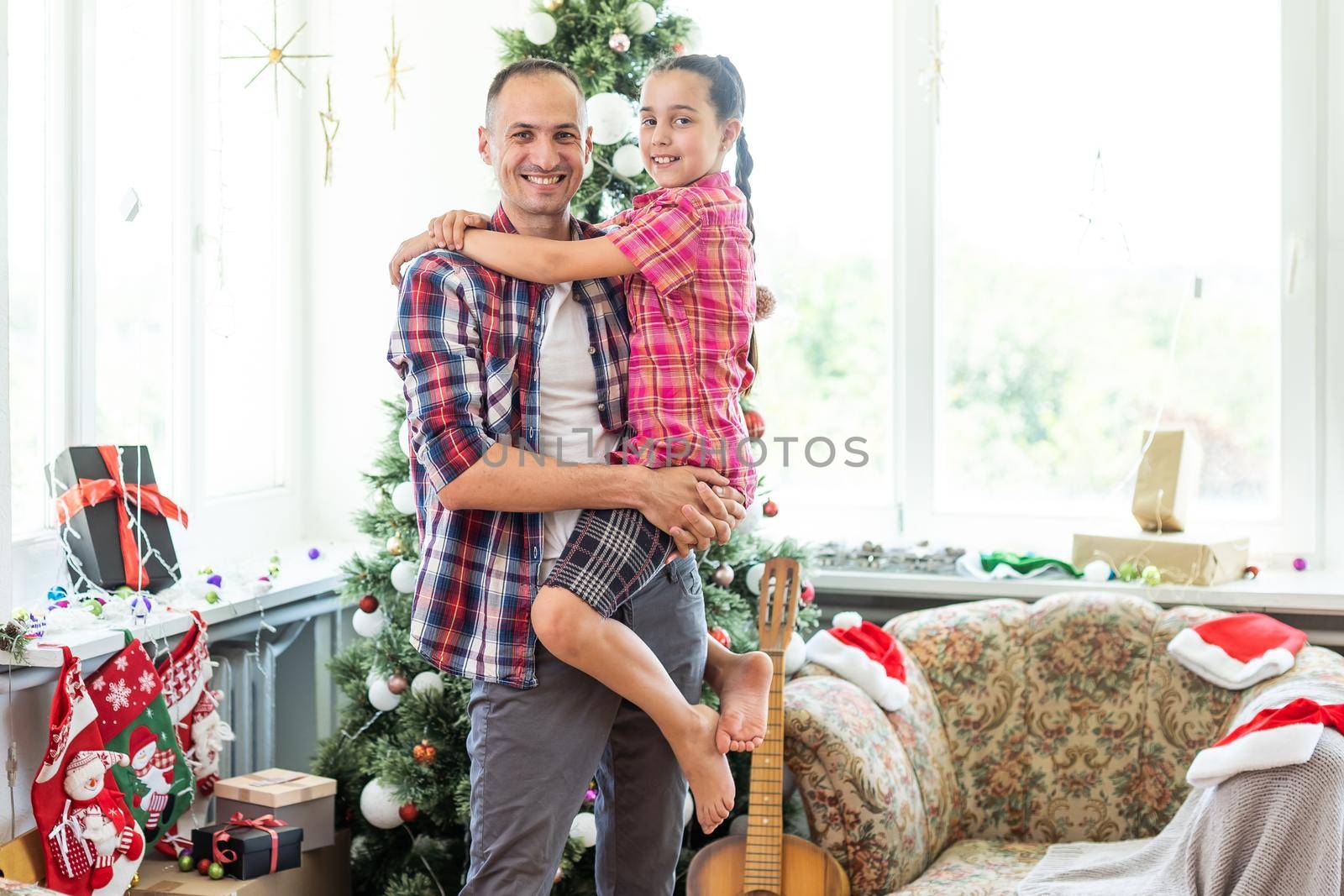 Happy father and his little daughter decorating the Christmas tree at home