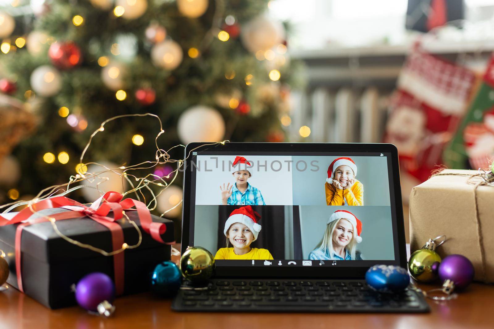 Christmas video call with happy family. Concept of families in quarantine during Christmas because of the coronavirus. Xmas still life with a tablet in a cozy room by Andelov13