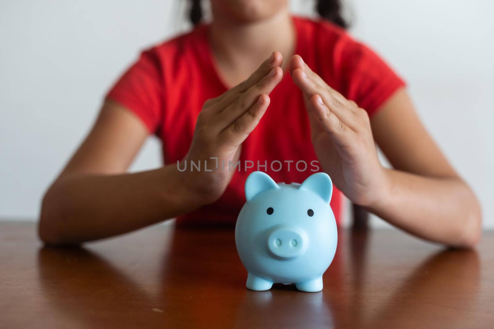 Little girl saving money in a piggybank over a white background.