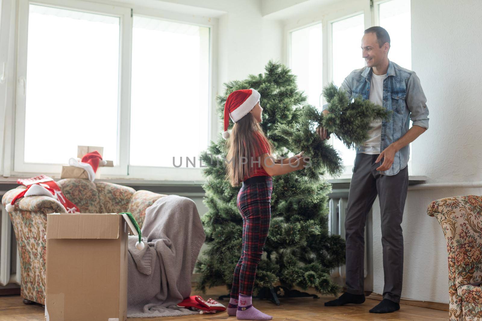 father and daughter install an artificial Christmas tree.