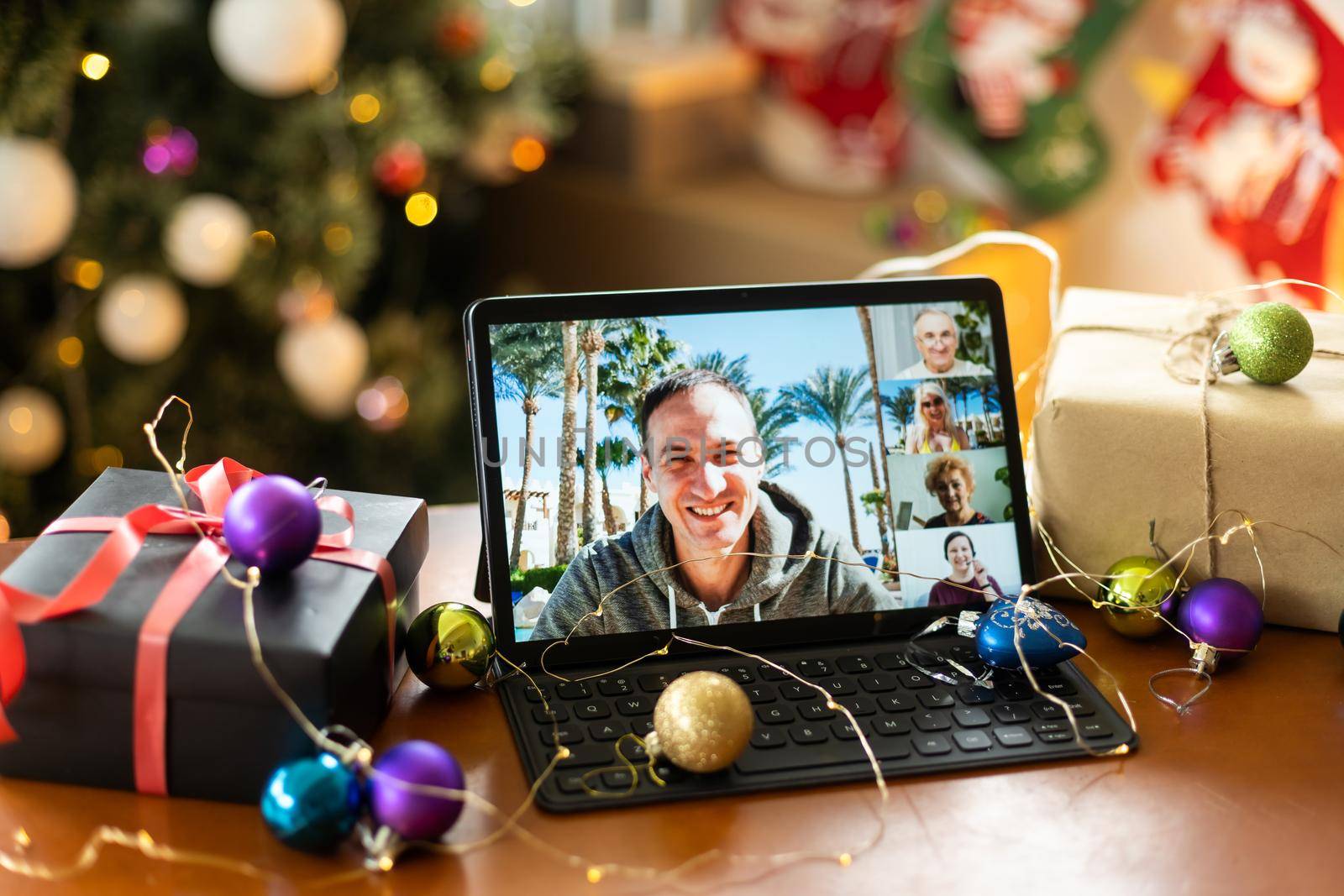 Family video call with kid presenting gift by remote chat digital tablet screen on Merry Christmas table holiday background. Xmas online virtual family party celebration, Happy New Year videocall by Andelov13