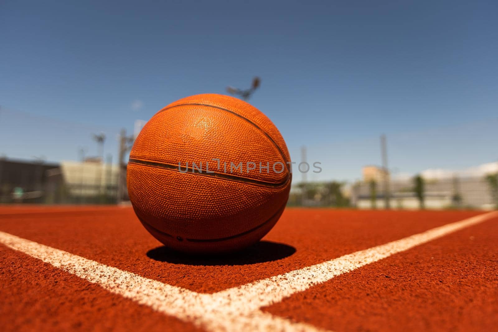 Top view orange ball for basketball lying on the rubber sport court. Sport red ground outdoor in the yard by Andelov13