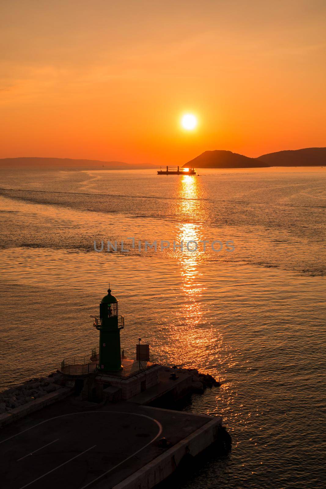 Sunset over the Adriatic Sea and its boats playing in the reflections at the entrance to the port of Split in Croatia.