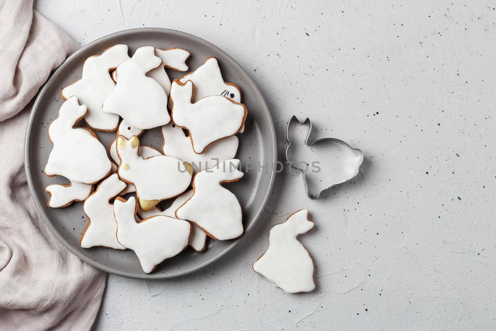 Easter cookies in the shape of a rabbit on a gray plate with gray textiles on a gray background. Copy space