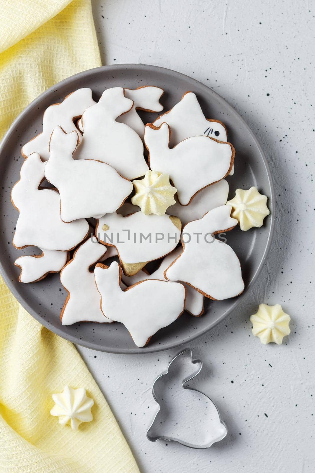 Easter cookies in the form of a rabbit on a gray plate with yellow textiles on a gray background. copy space,vertical photo