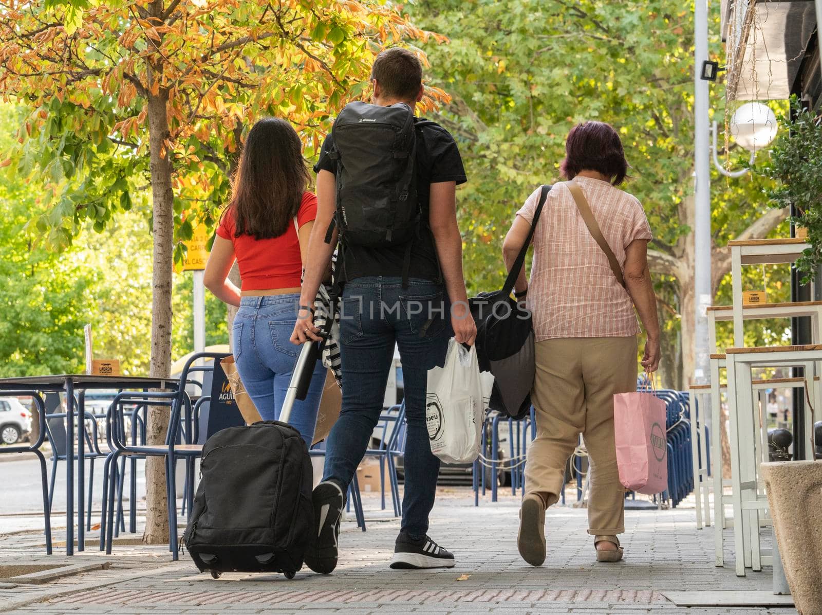 Family returning from vacation walking on the street. Adult and brothers or couple with luggage after holidays or returning from shopping.