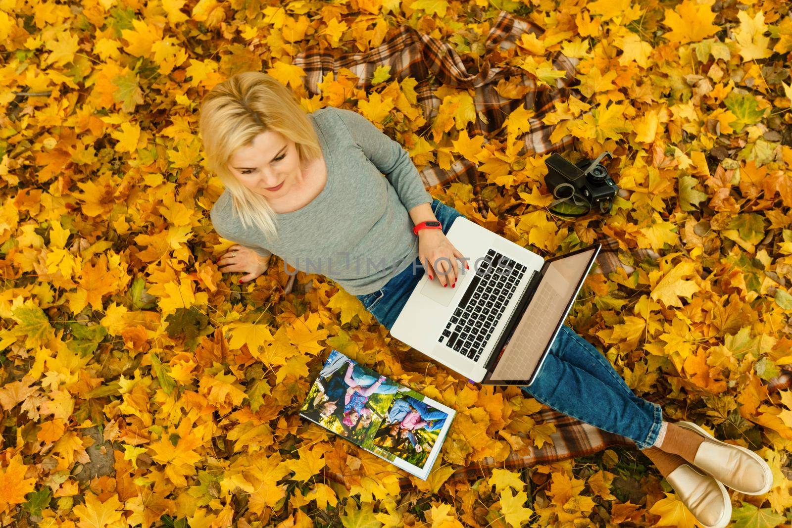 woman with laptop and photo book in autumn park by Andelov13