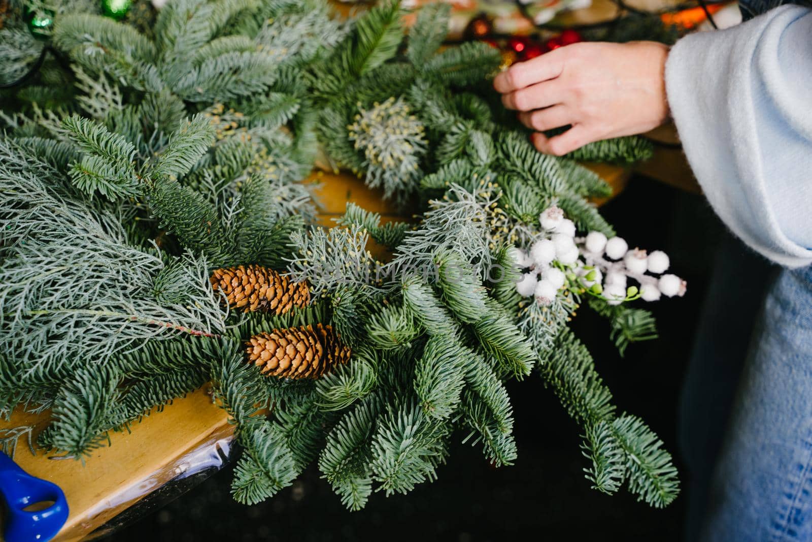 Concept of florist's work before christmas holidays. Creating a Christmas wreath of spruce branches and a cardboard frame. A wreath of coniferous branches with your own hands.