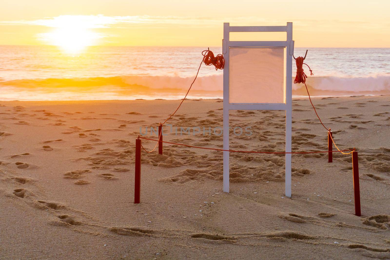 White information board on the beach at sunset