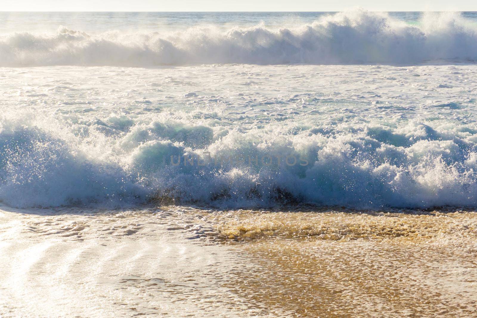 Ocean waves with white foam on a sunny day background