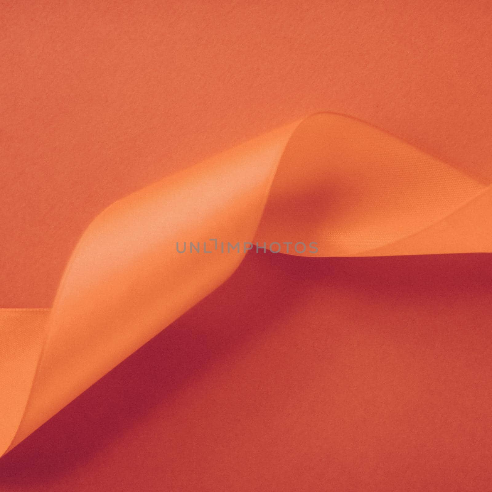 Branding, holidays and luxe brands concept - Abstract curly silk ribbon on orange background, exclusive luxury brand design for holiday sale product promotion and glamour art invitation card backdrop