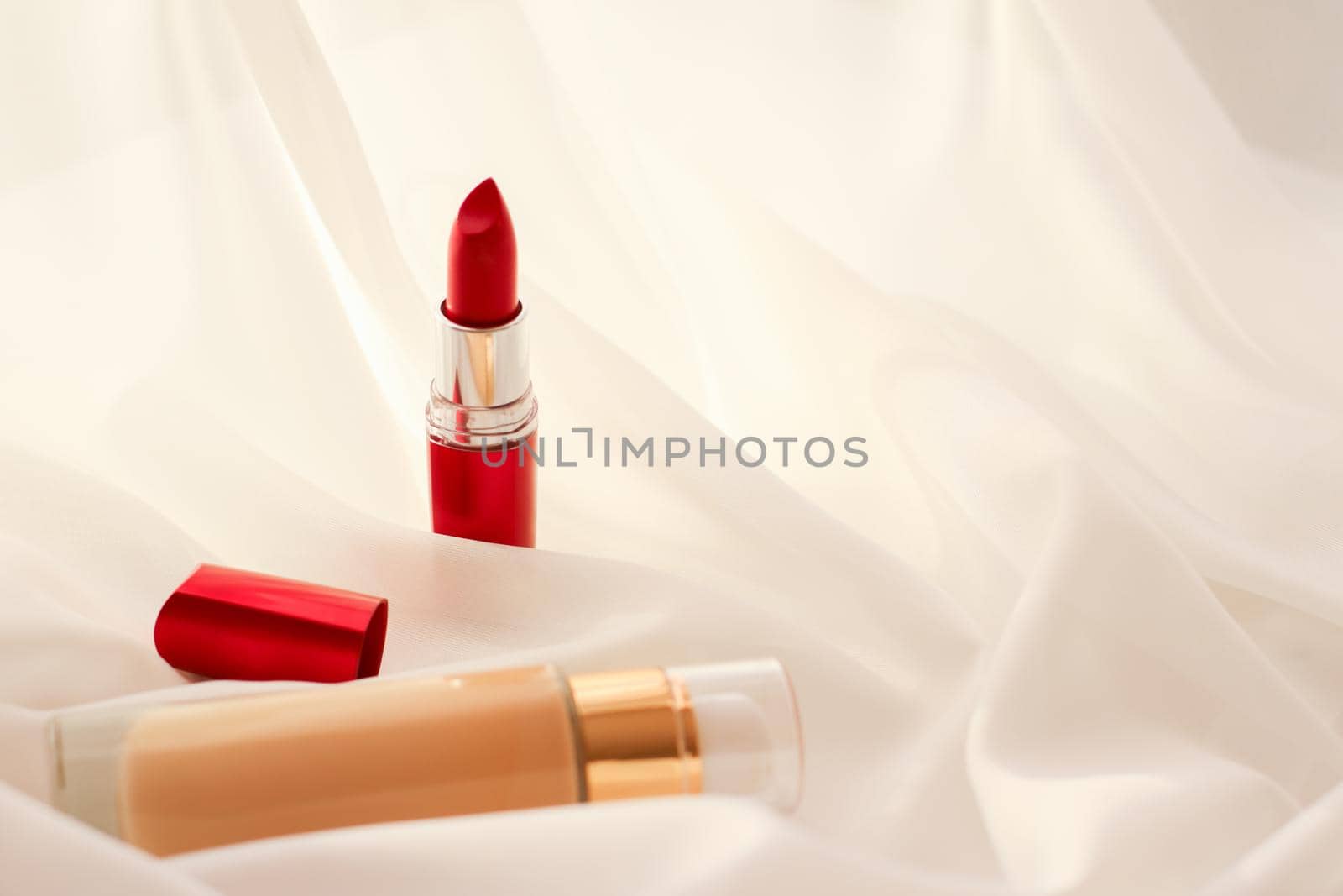 Cosmetic branding, glamour and skincare concept - Beige tonal cream bottle make-up fluid foundation base and red lipstick on silk background, cosmetics products as luxury beauty brand holiday design