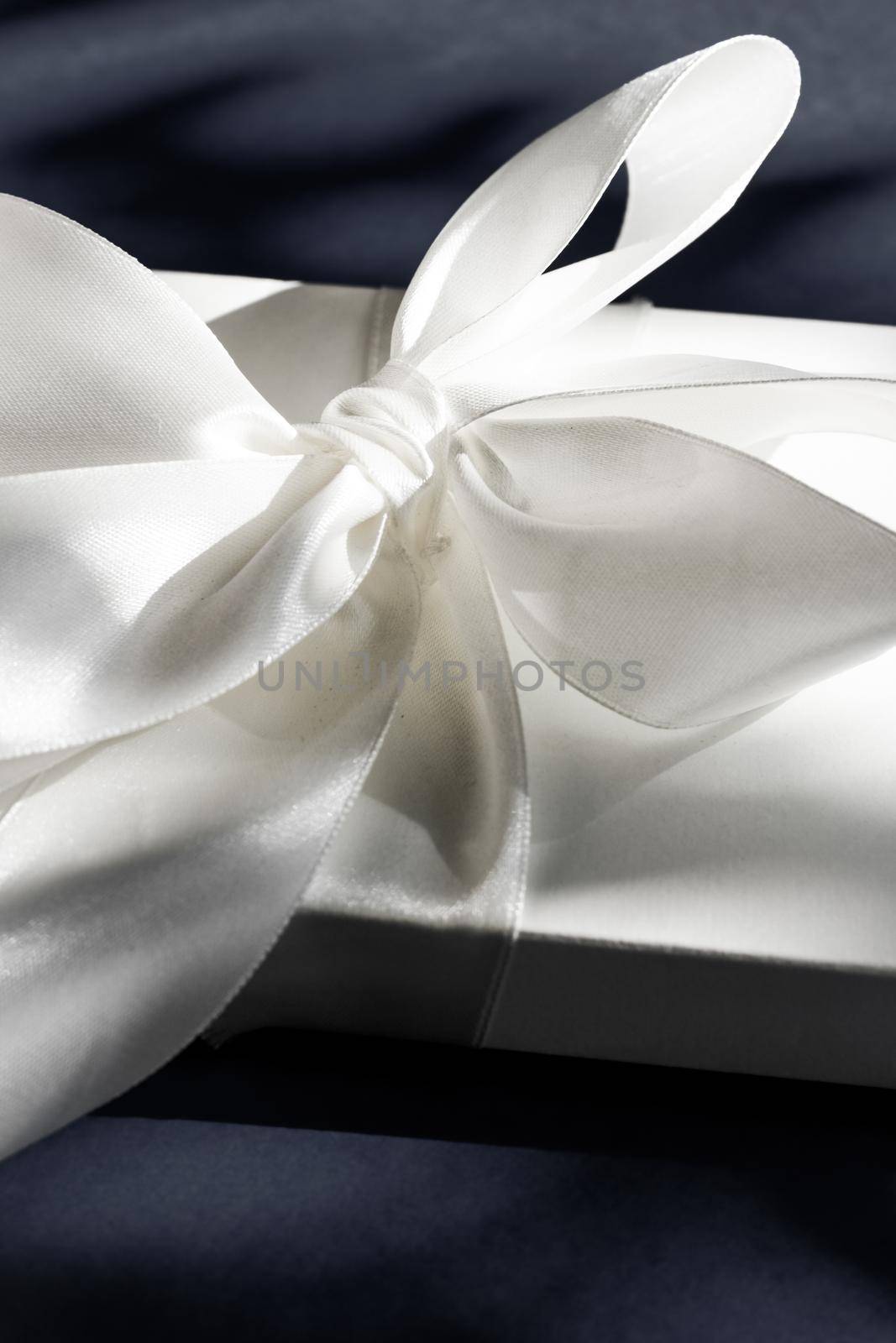 Luxury holiday white gift box with silk ribbon and bow on black background, luxe wedding or birthday present by Anneleven