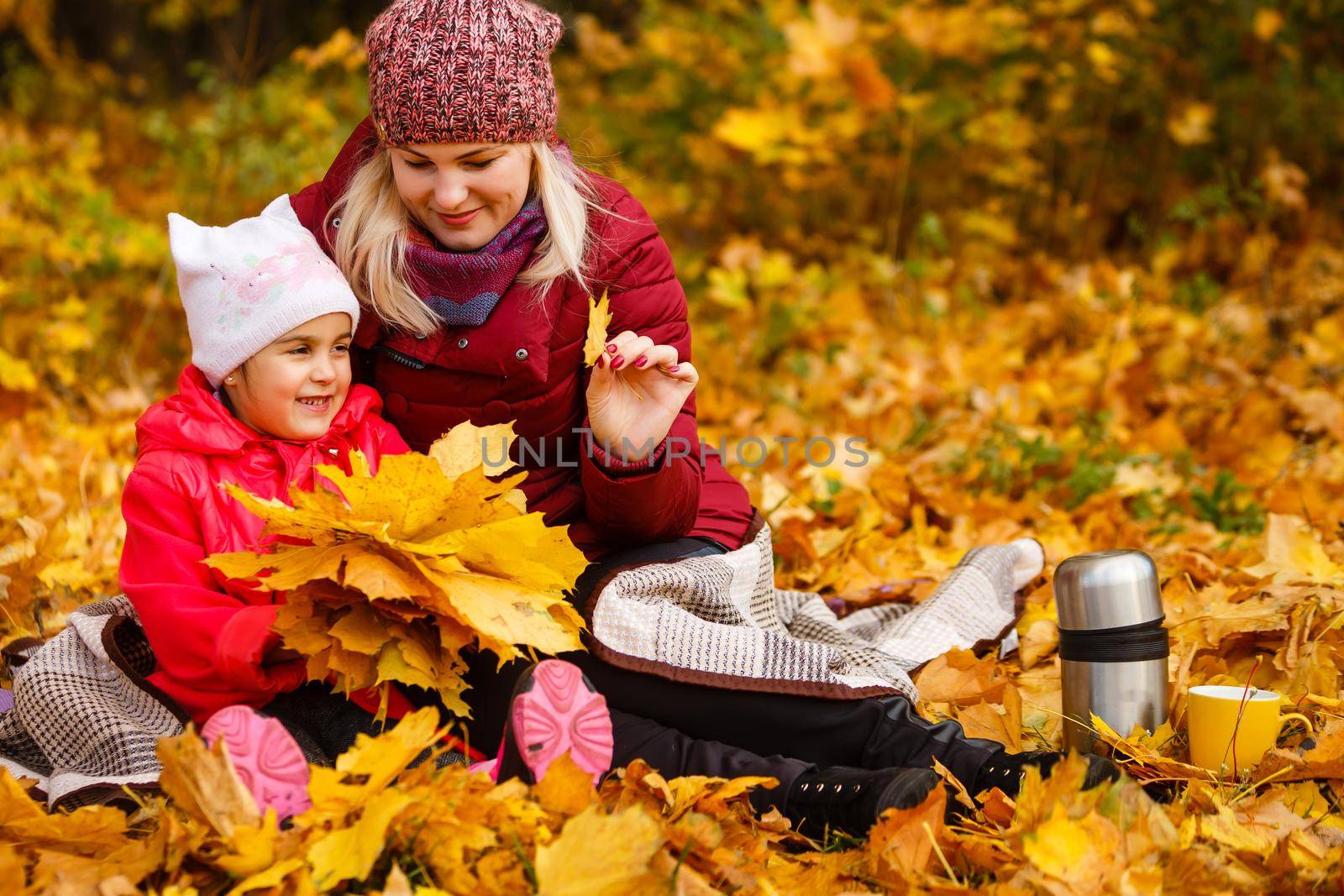 Young mother with her little daughter in an autumn park.