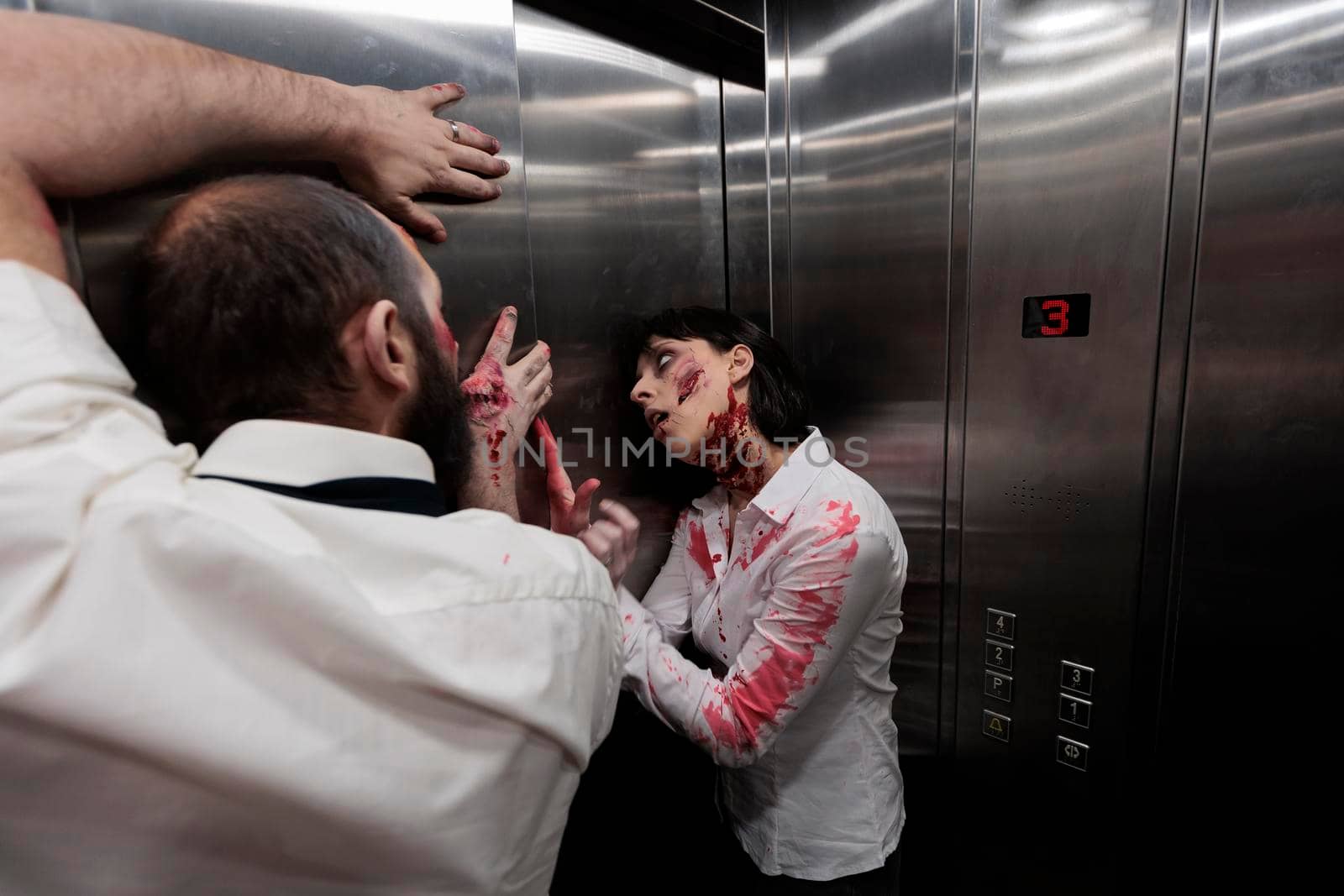 Scary evil zombies crawling on elevator walls, preparing terrifying sinister attack in company office. Brain eating walking dead killers looking aggressive and dangerous with bloody scars.