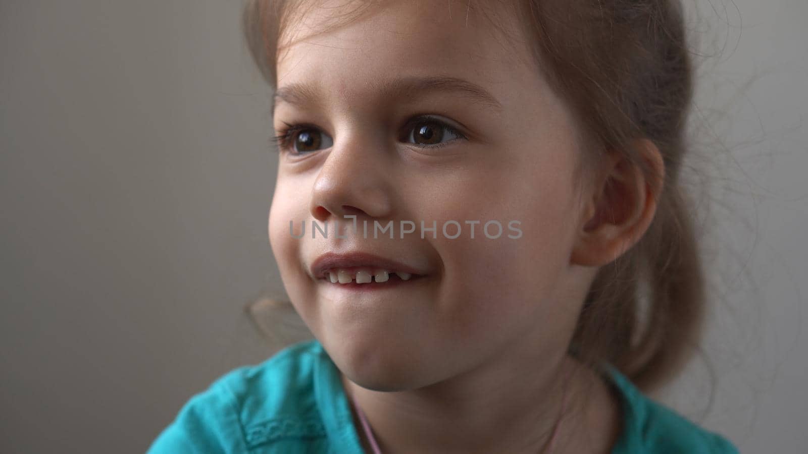 Portrait Funny little close up view happy preschool girl smiling child looking away thoughtfully, pretty natural face.sincere emotions of ashamed, embarrassed clean skin dermatology, pediatric dentistry